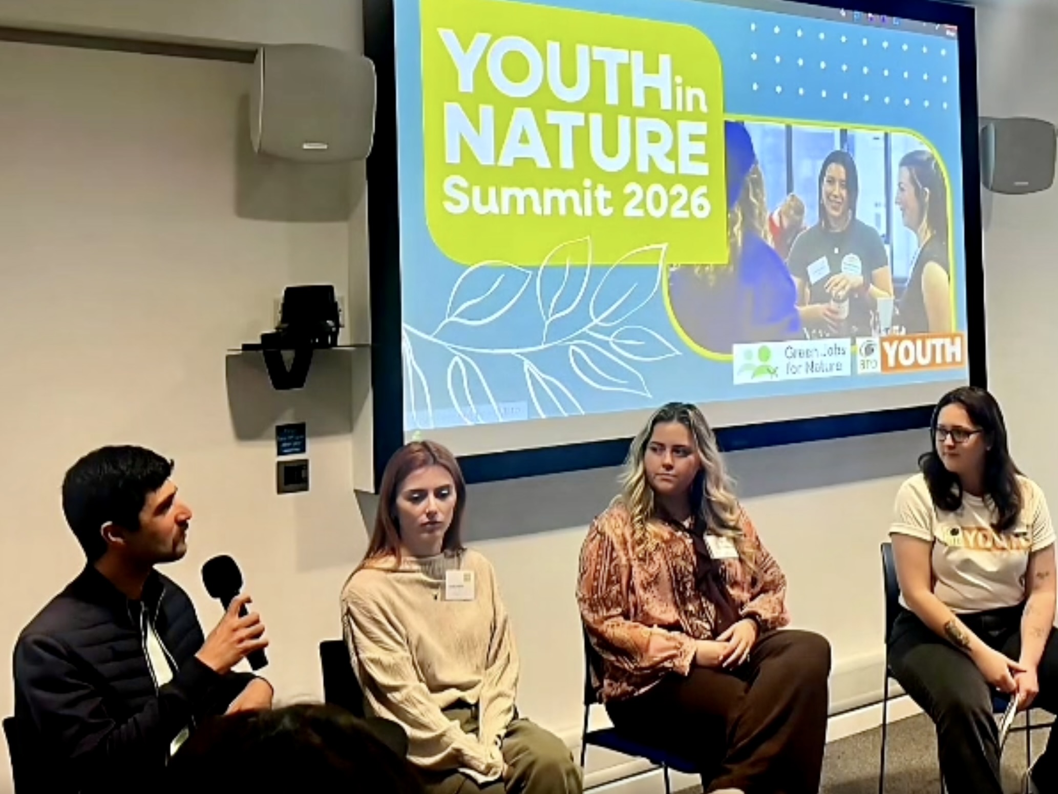 Ajay Tegala at the BTO Youth In Nature Summit A man and three young women seated in front of a screen that says Youth in Nature Summit on it