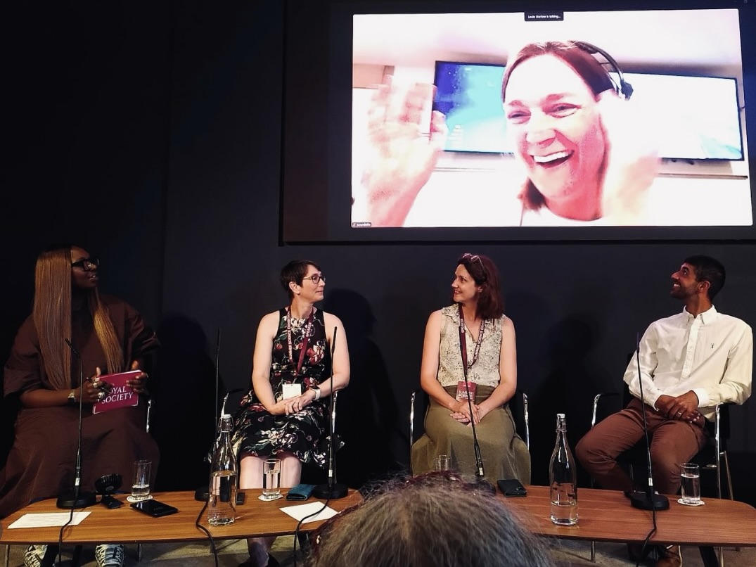 Ajay Tegala on a panel at the Royal Society Three women and a man sat on a stage with a fourth woman on a screen behind them